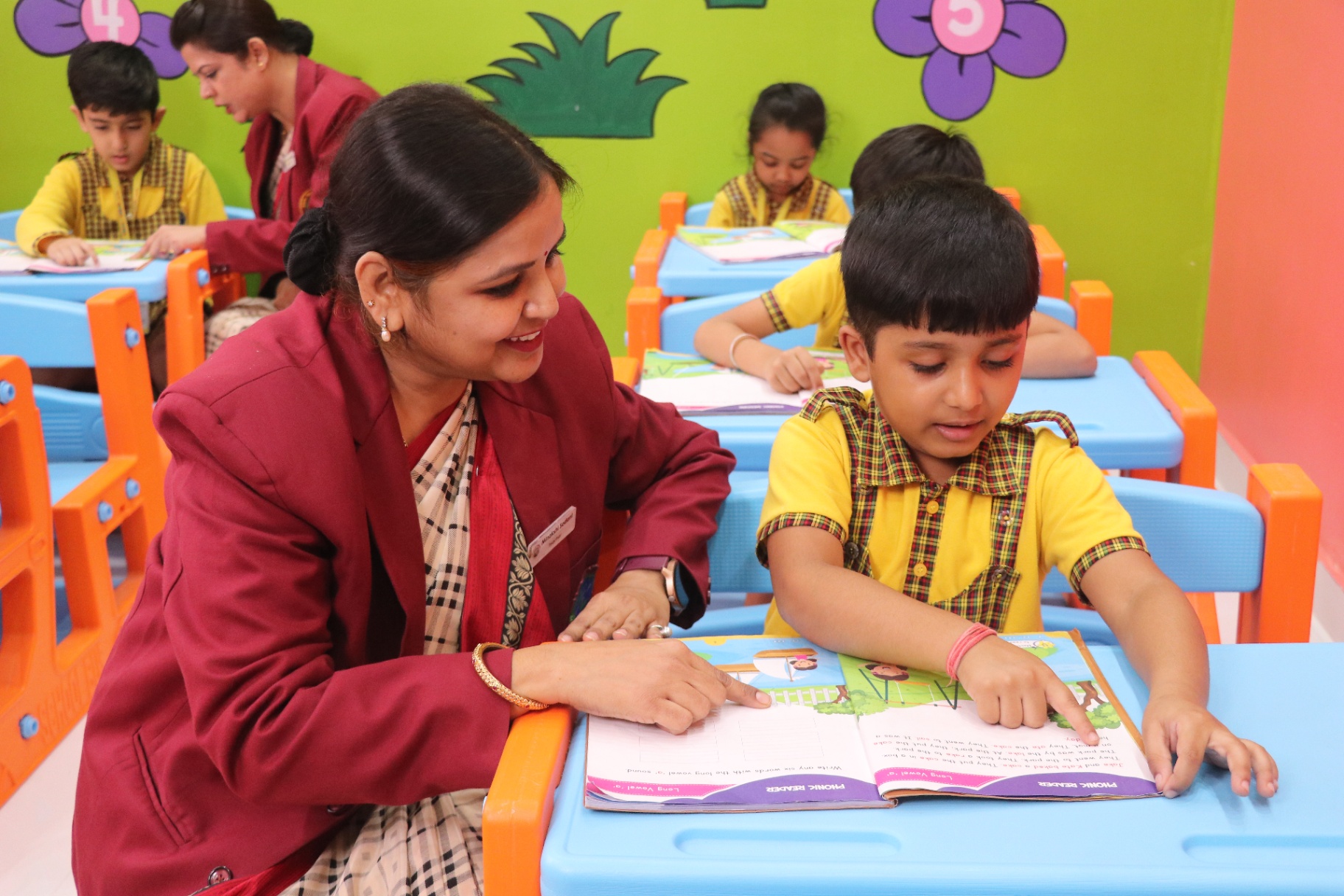 A teacher encourages a young child during a phonics lesson